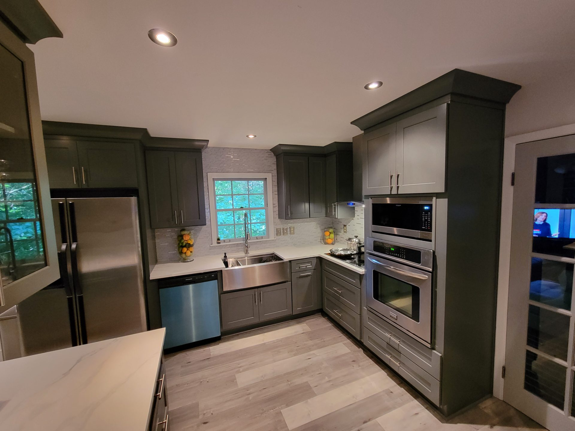 Kitchen with deep green cabinets, a farmhouse sink and a wall oven in Norcross
