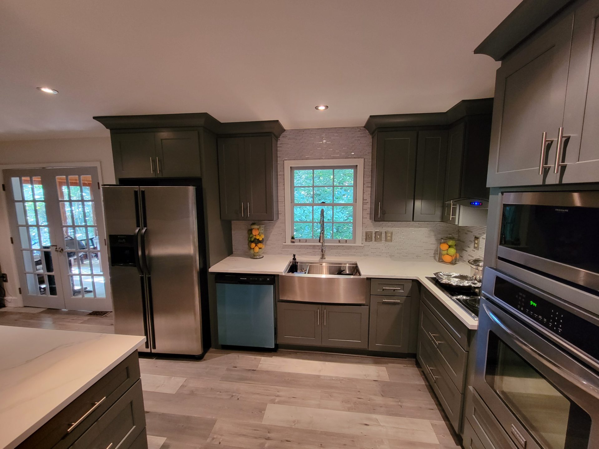 Kitchen with deep green cabinets, a farmhouse sink and a wall oven in Marietta