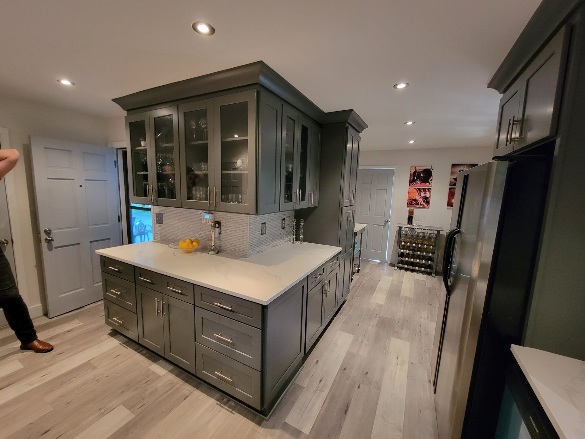 Kitchen with deep green cabinets, a farmhouse sink and a wall oven in Lilburn