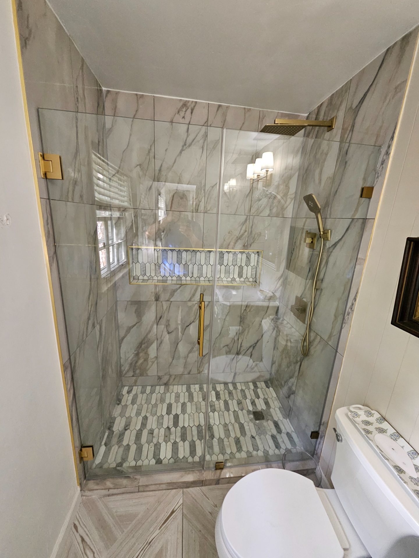 Marble-walled bathroom with a double vanity and a gold shower fixture in Peachtree Corners