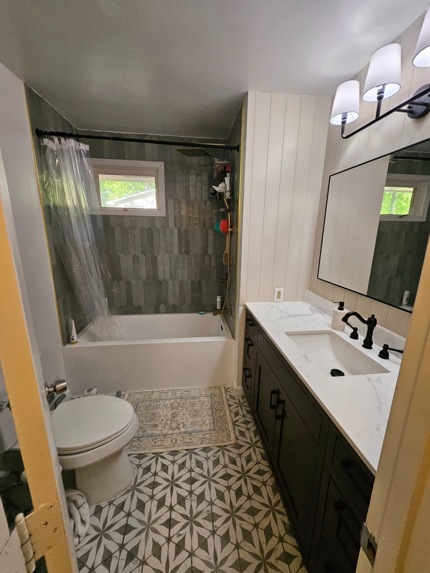 Bathroom with a tiled tub surround, vanity and large mirror