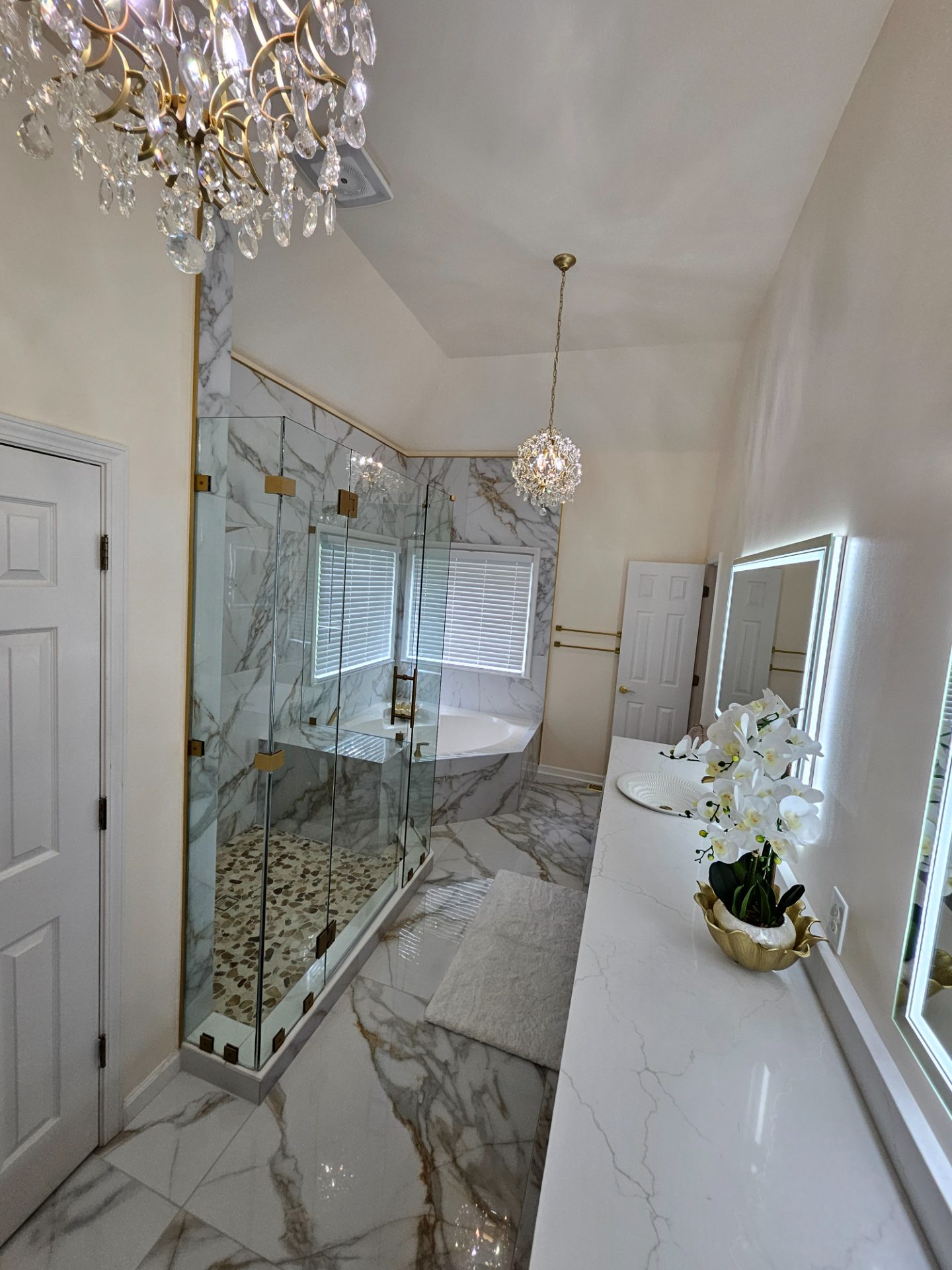 Bathroom with a lit mirror, marble tile and a freestanding tub in Suwanee