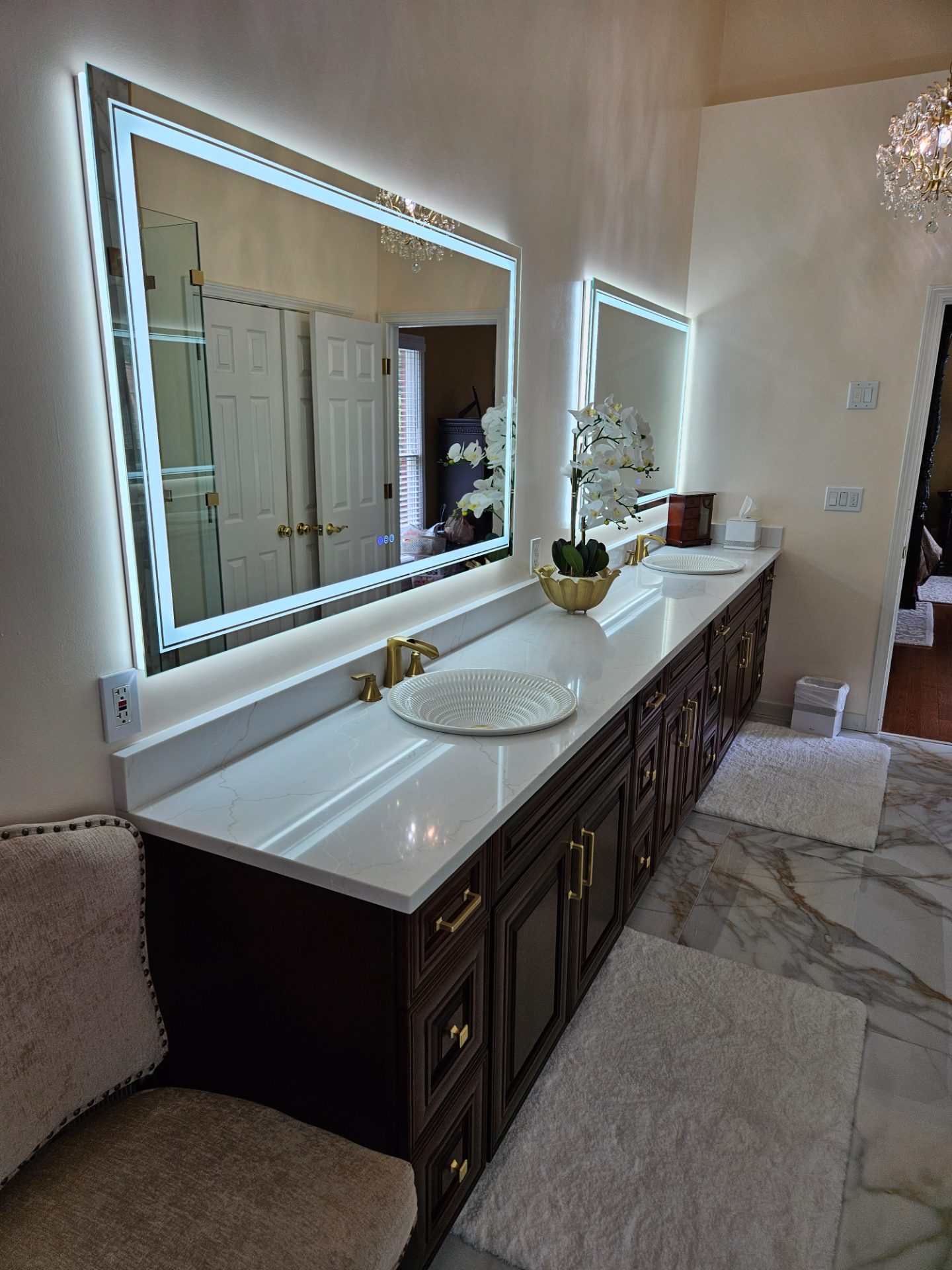 Bathroom with a lit mirror, marble tile and a freestanding tub