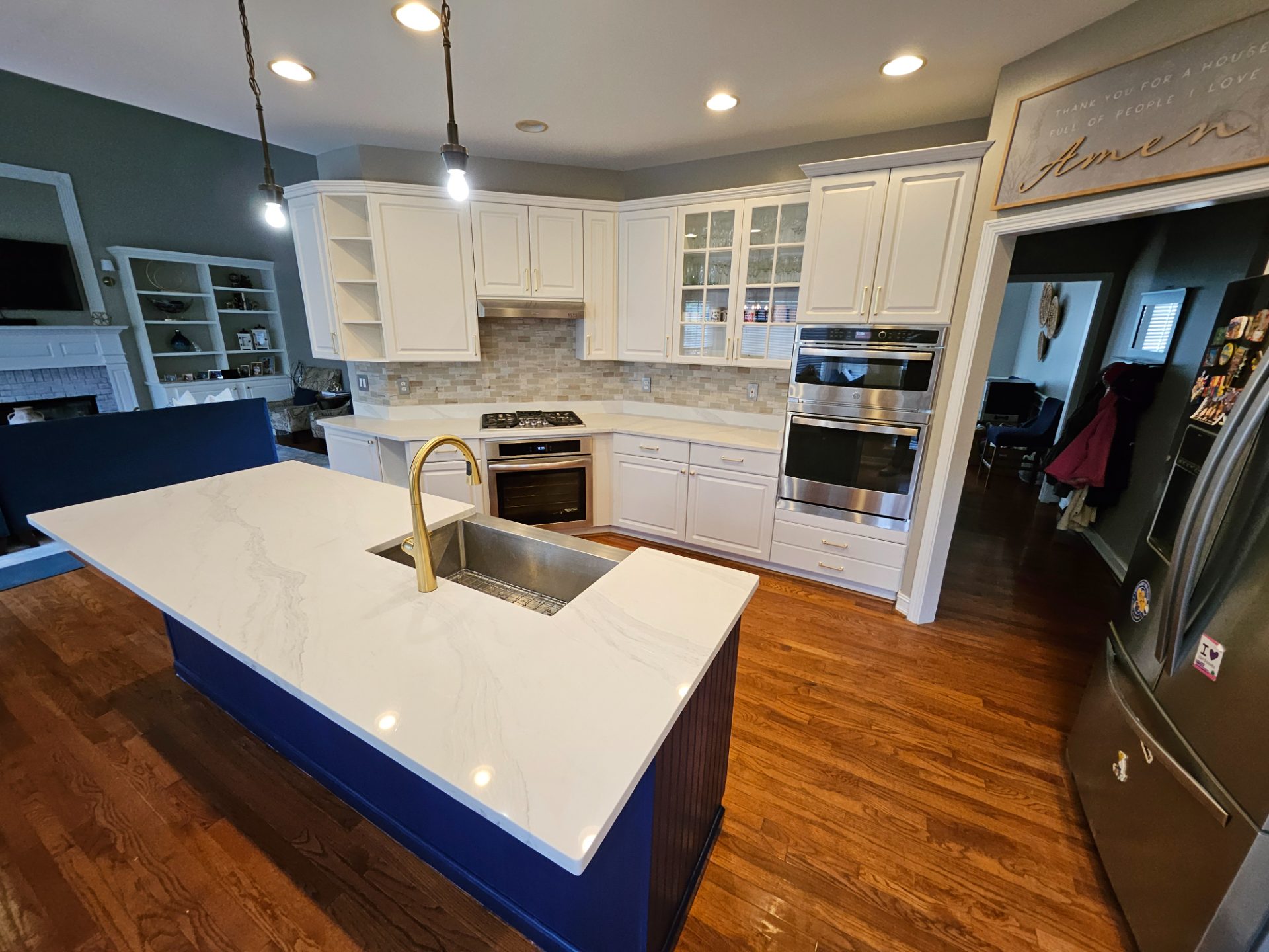 White kitchen with a navy island, stone counters and a gold faucet in Coal Mountain