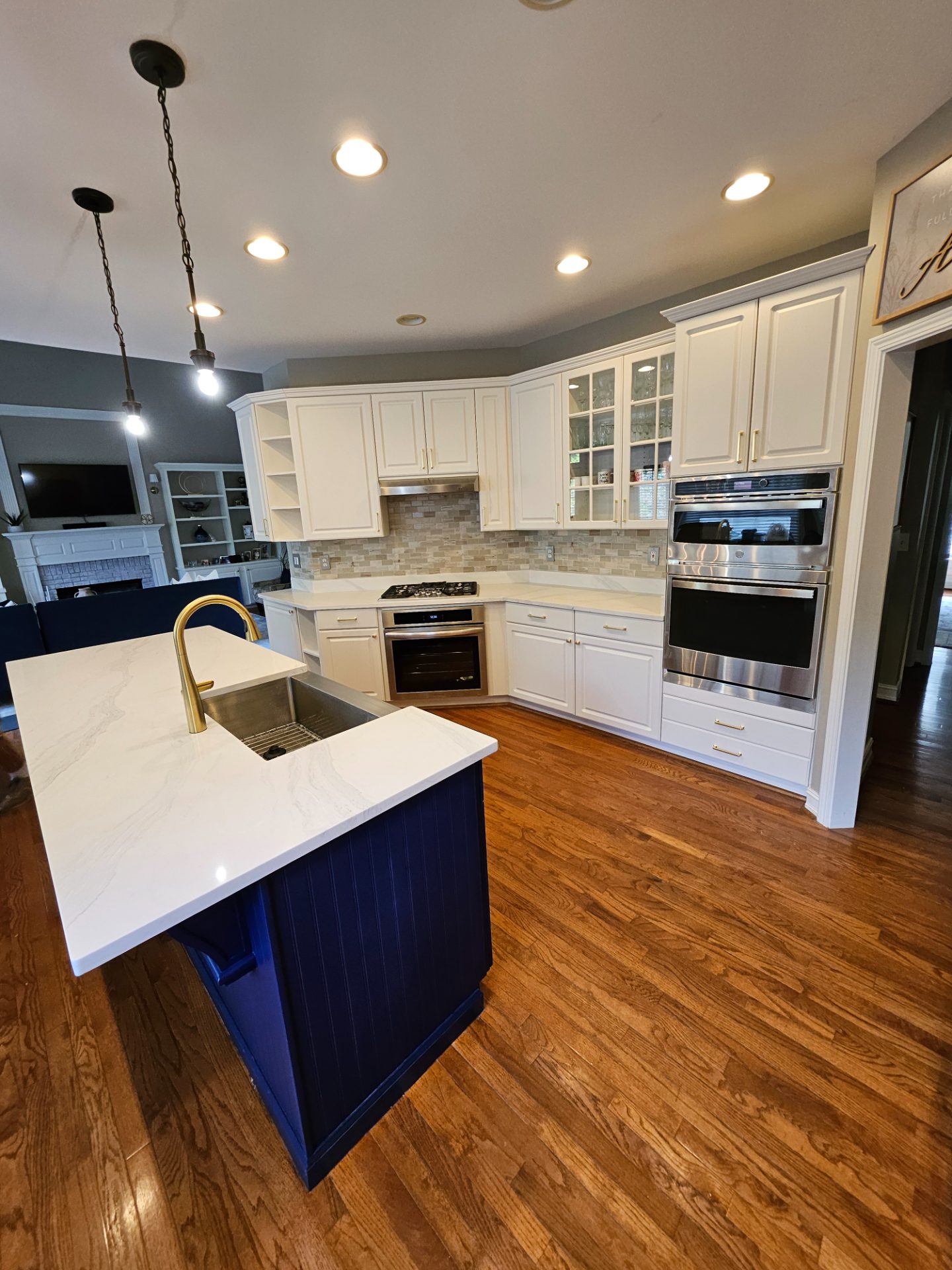 White kitchen with a navy island, stone counters and a gold faucet in Stonecrest