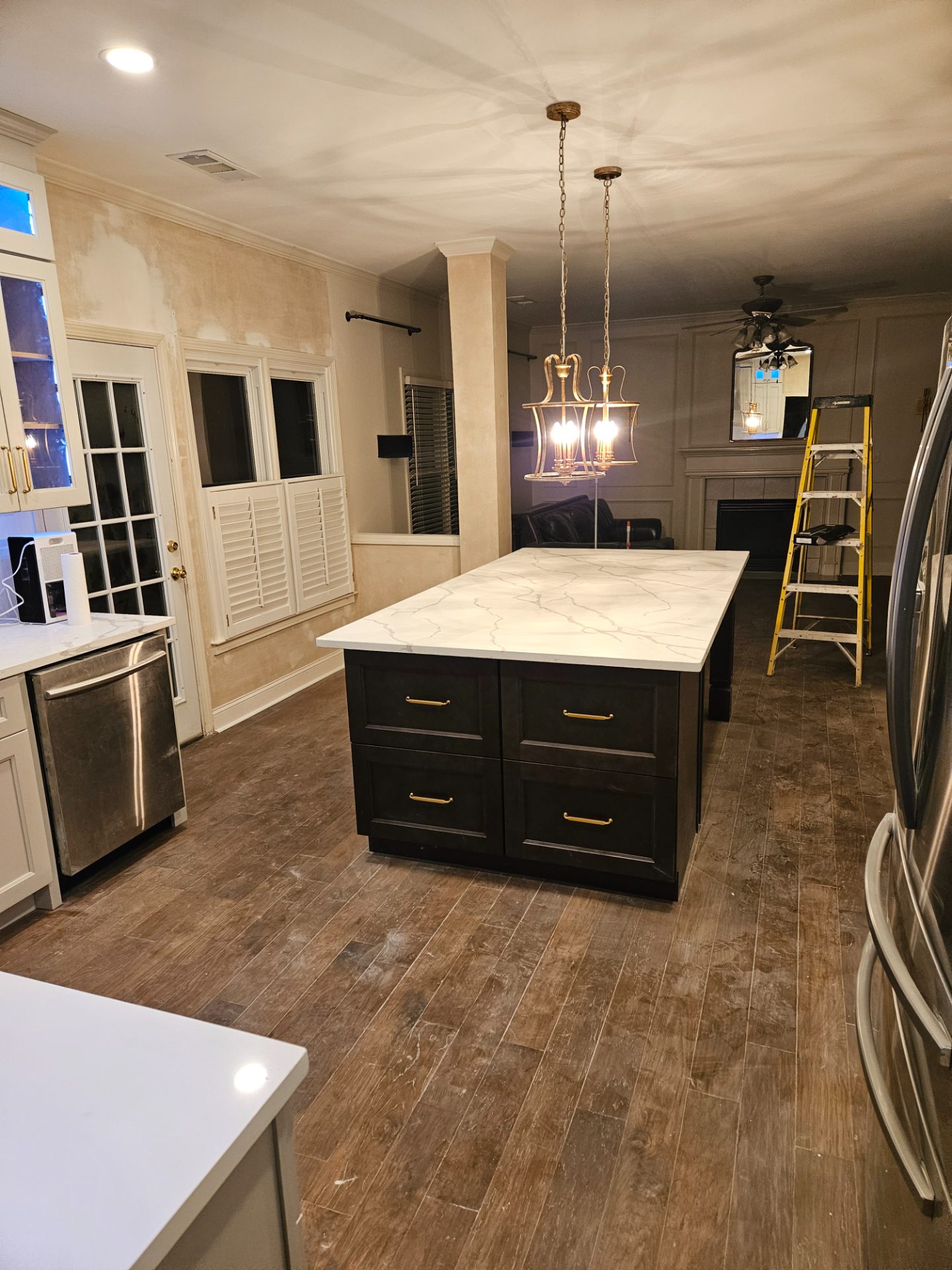 Kitchen with a marble island, dark base cabinets and a lantern pendant in Marietta