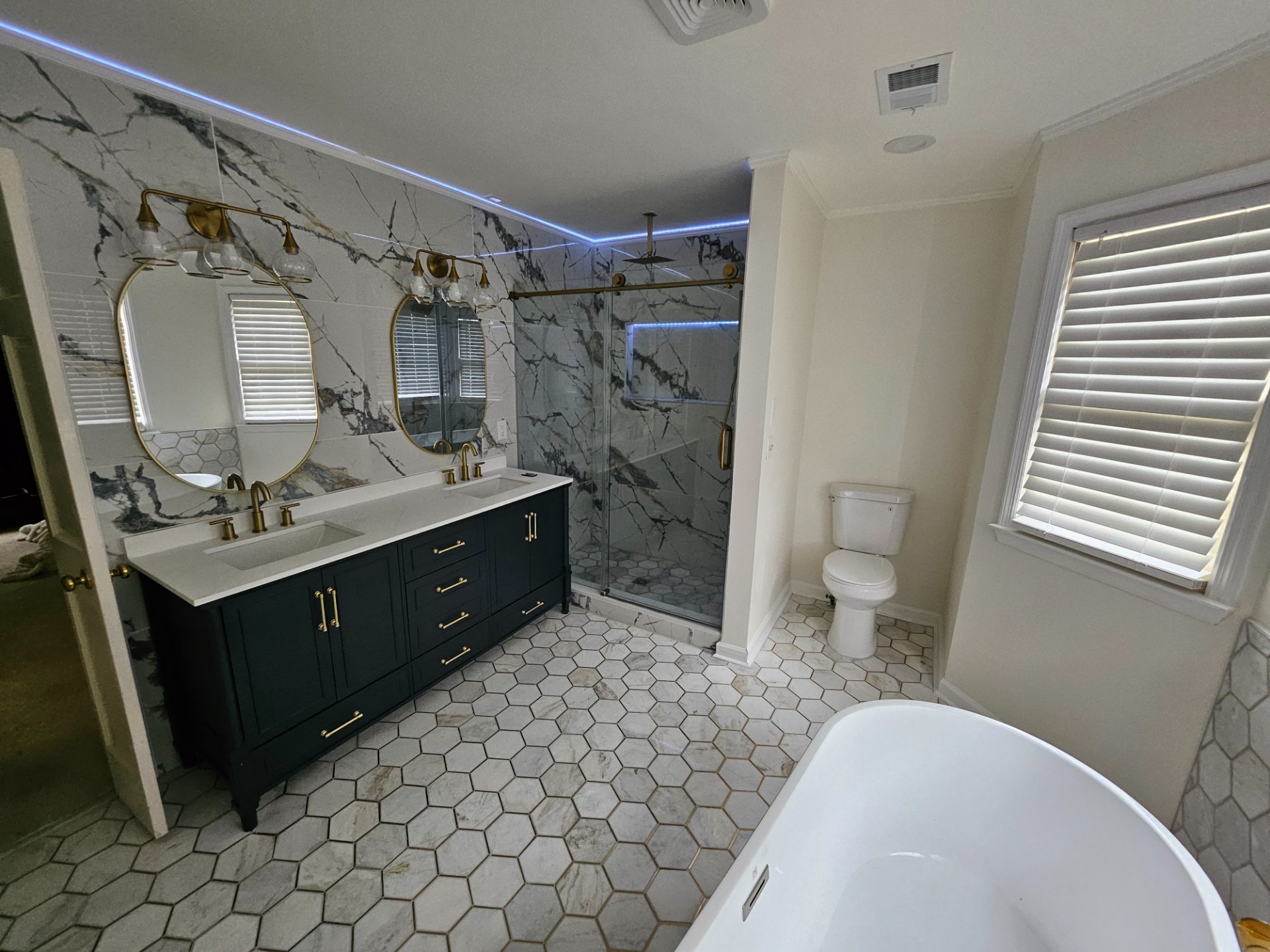 Bathroom with a green vanity, freestanding tub and hex-tile floor