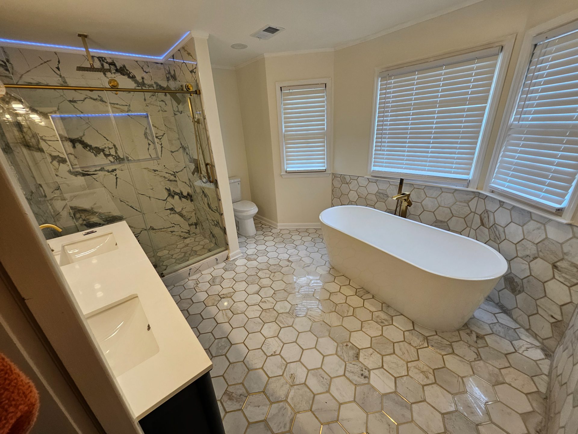 Bathroom with a green vanity, freestanding tub and hex-tile floor