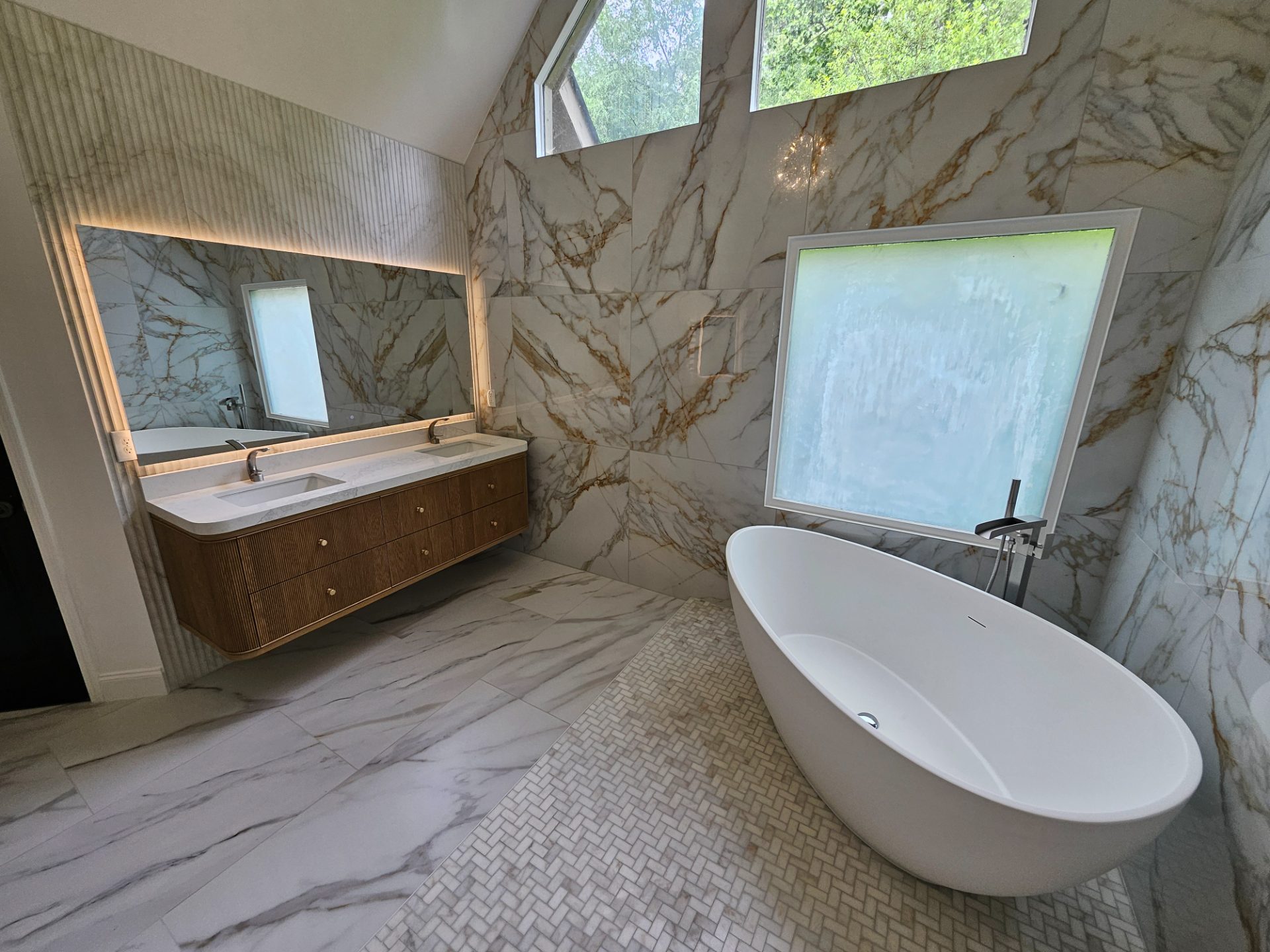 Marble bathroom with a freestanding tub under a vaulted ceiling