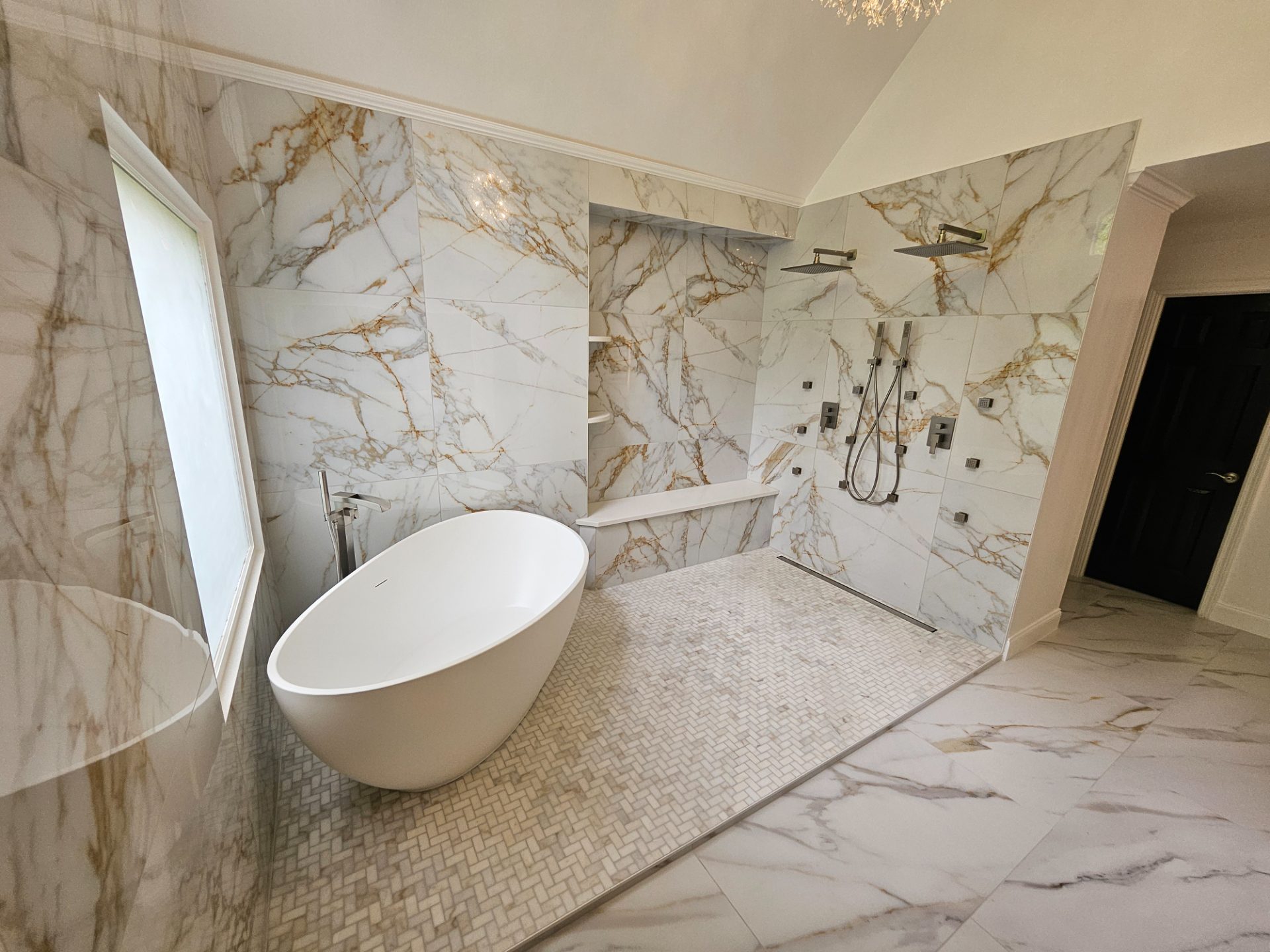 Marble-look tile bathroom with a freestanding tub and a curbless shower with twin rain heads