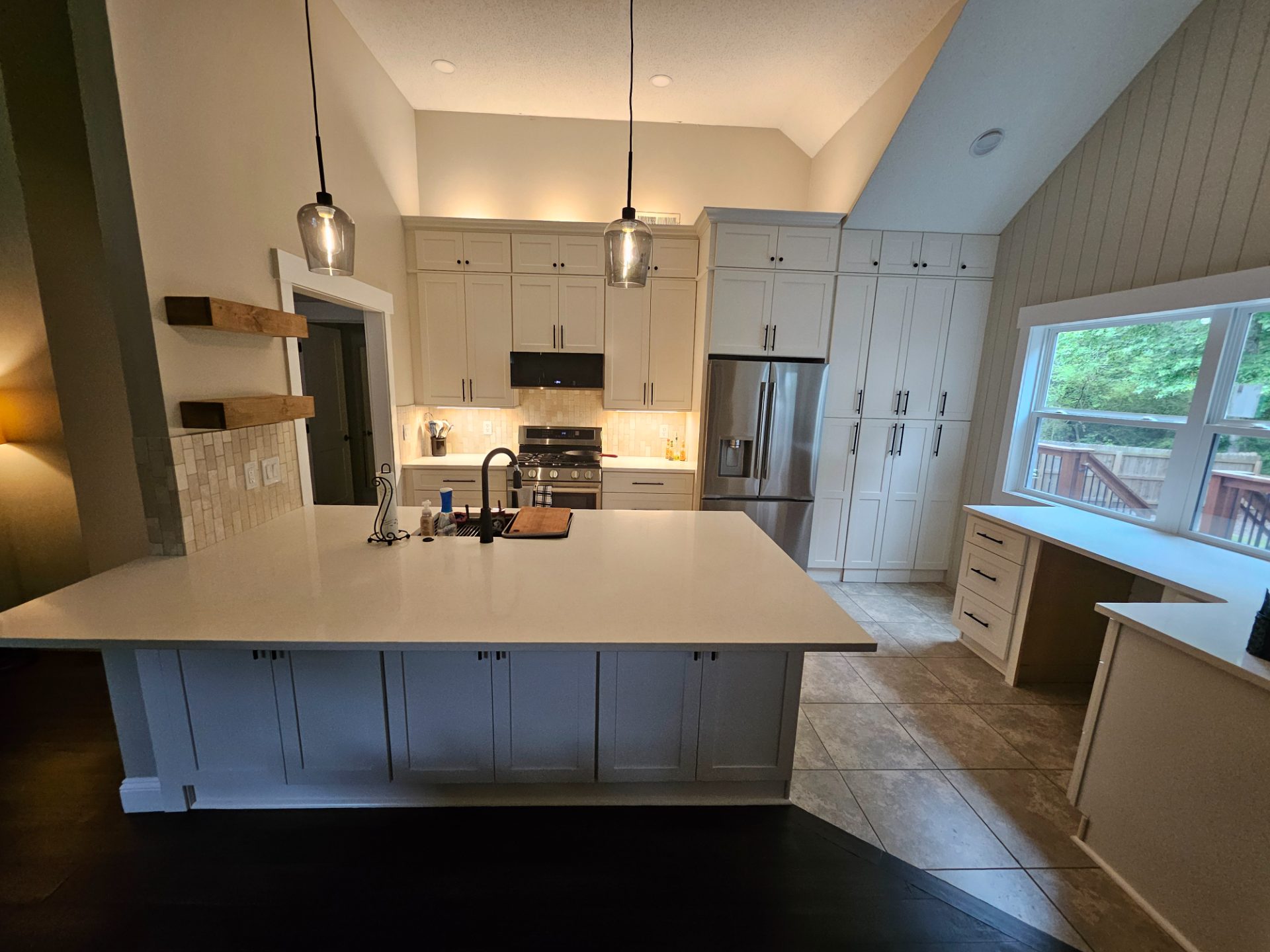 Kitchen with shiplap walls, a vaulted ceiling and a stone island in Lilburn