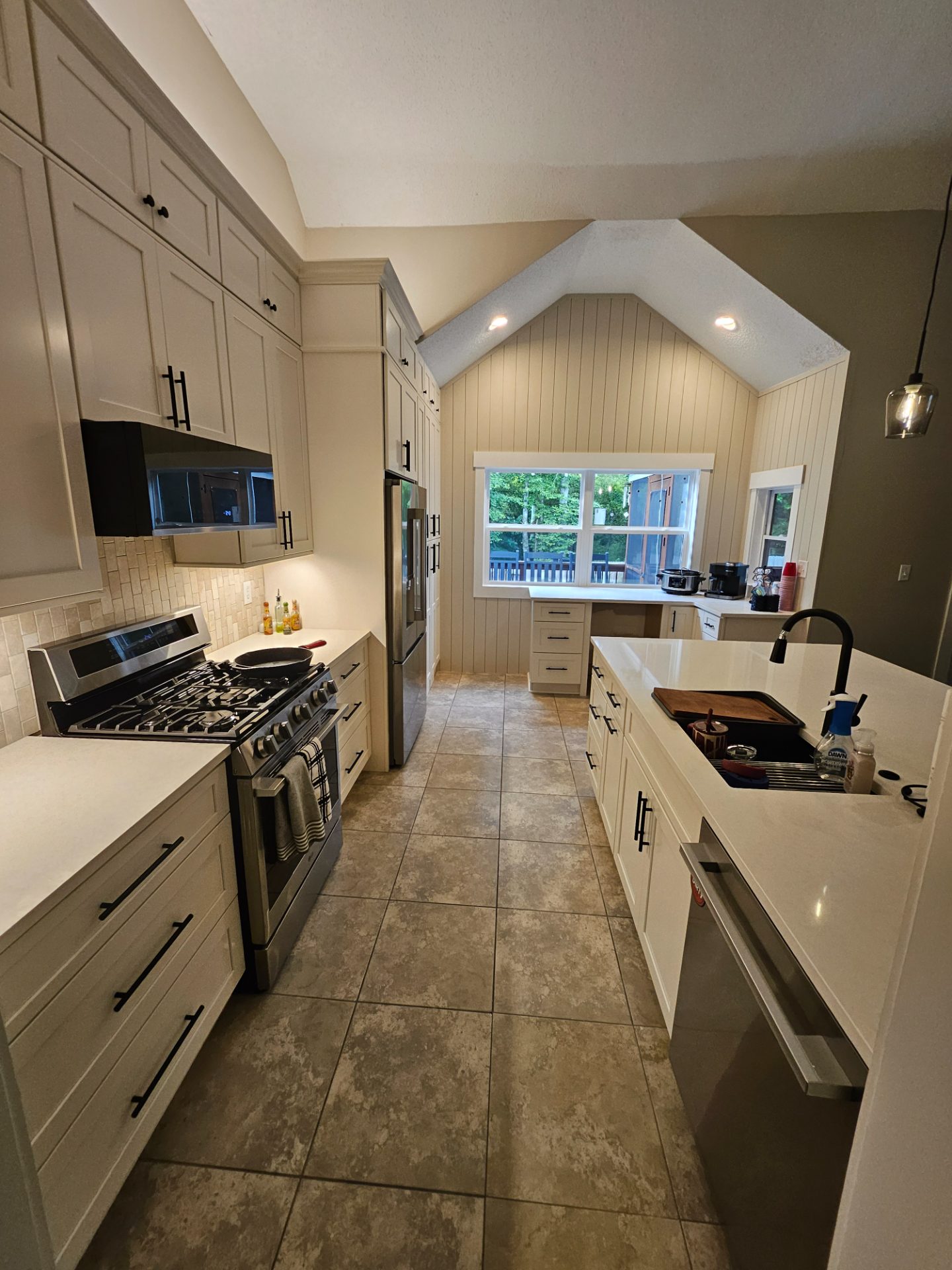Kitchen with shiplap walls, a vaulted ceiling and a stone island in Austell
