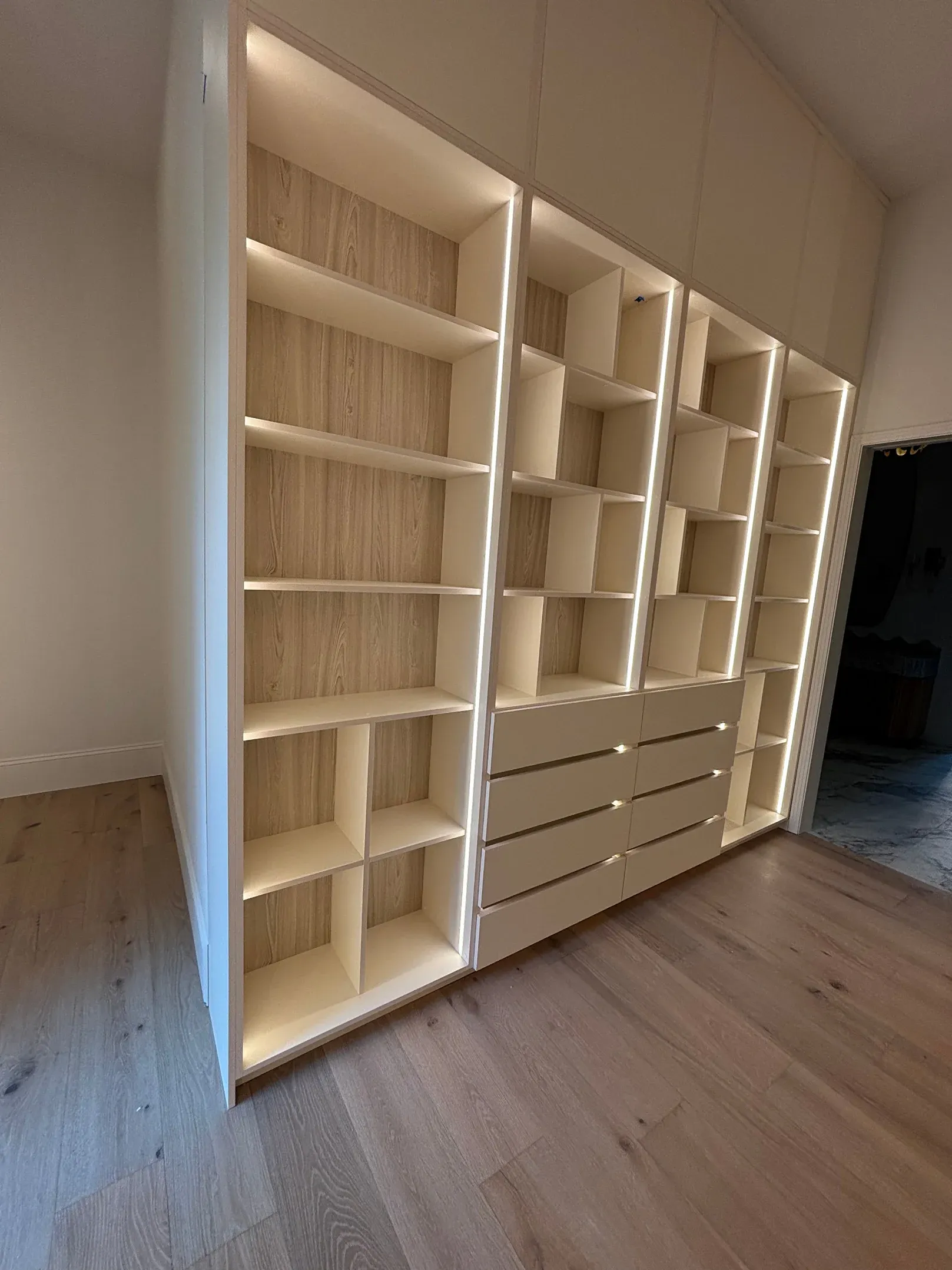 Full-height white shelving running the length of a wall