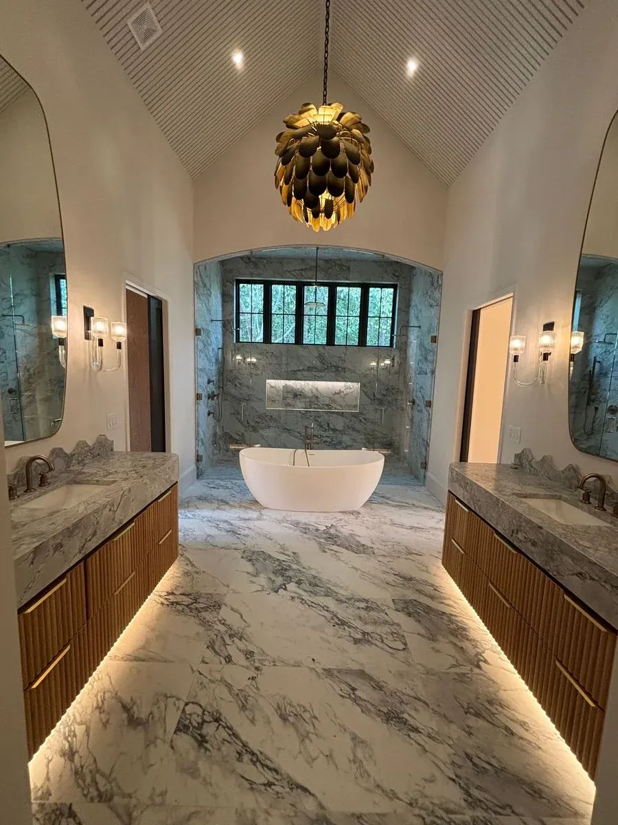 Marble bathroom with a double vanity, wall sconces and a freestanding tub in Peachtree Corners