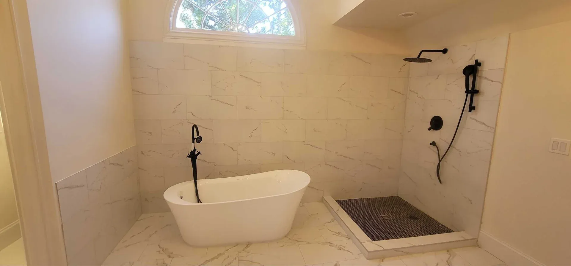 White tiled bathroom with a freestanding tub and a wall-mounted filler in Johns Creek