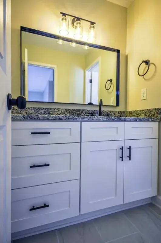 Double vanity with granite top, black hardware and a framed mirror