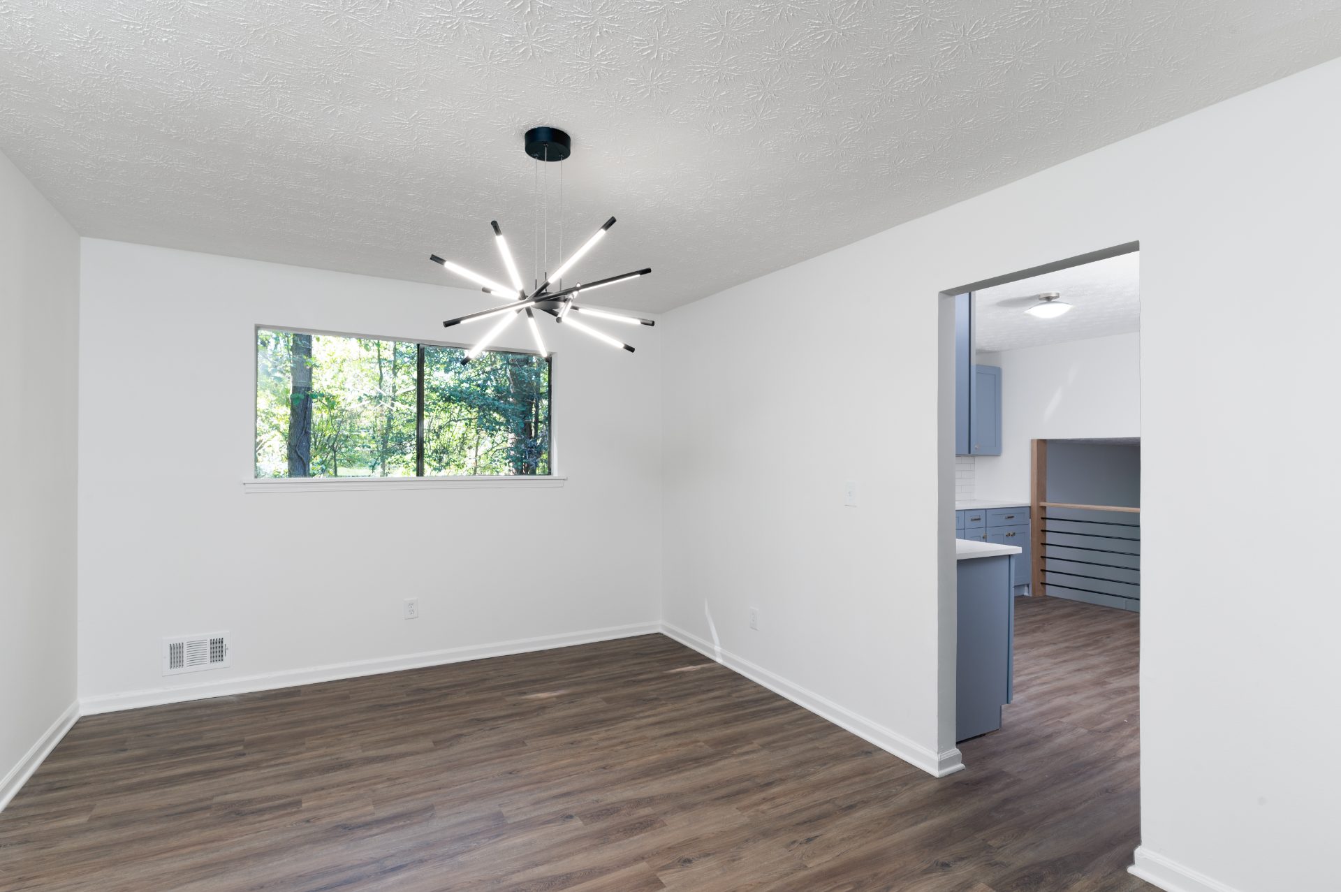 Renovated room with new plank flooring and a modern light fixture in Norcross