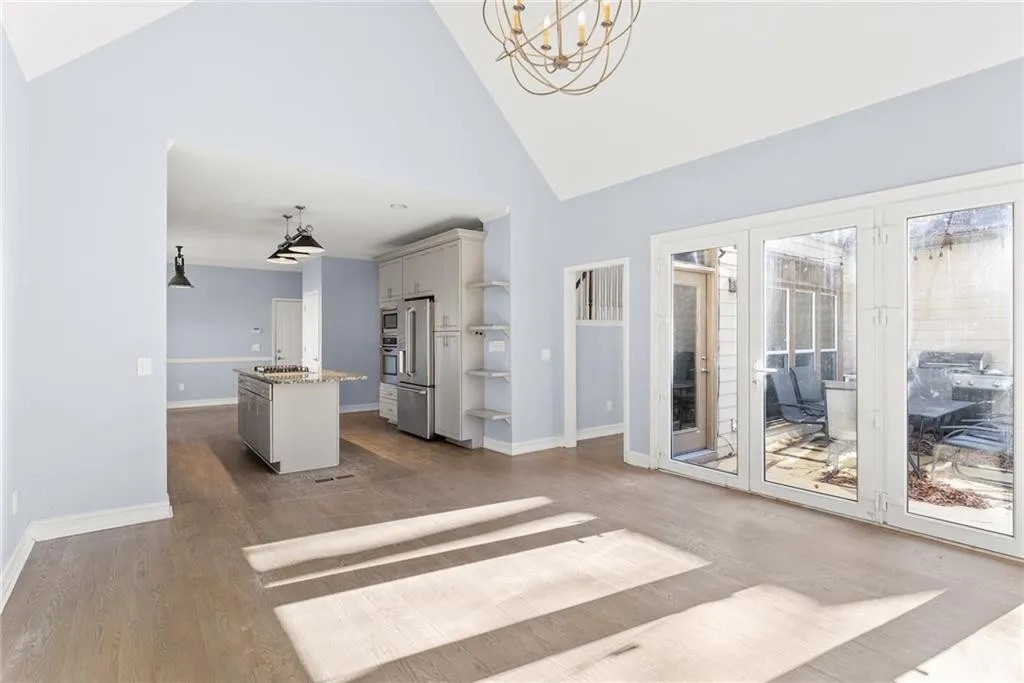 Vaulted family room open to a kitchen with a gray island and French doors to a patio