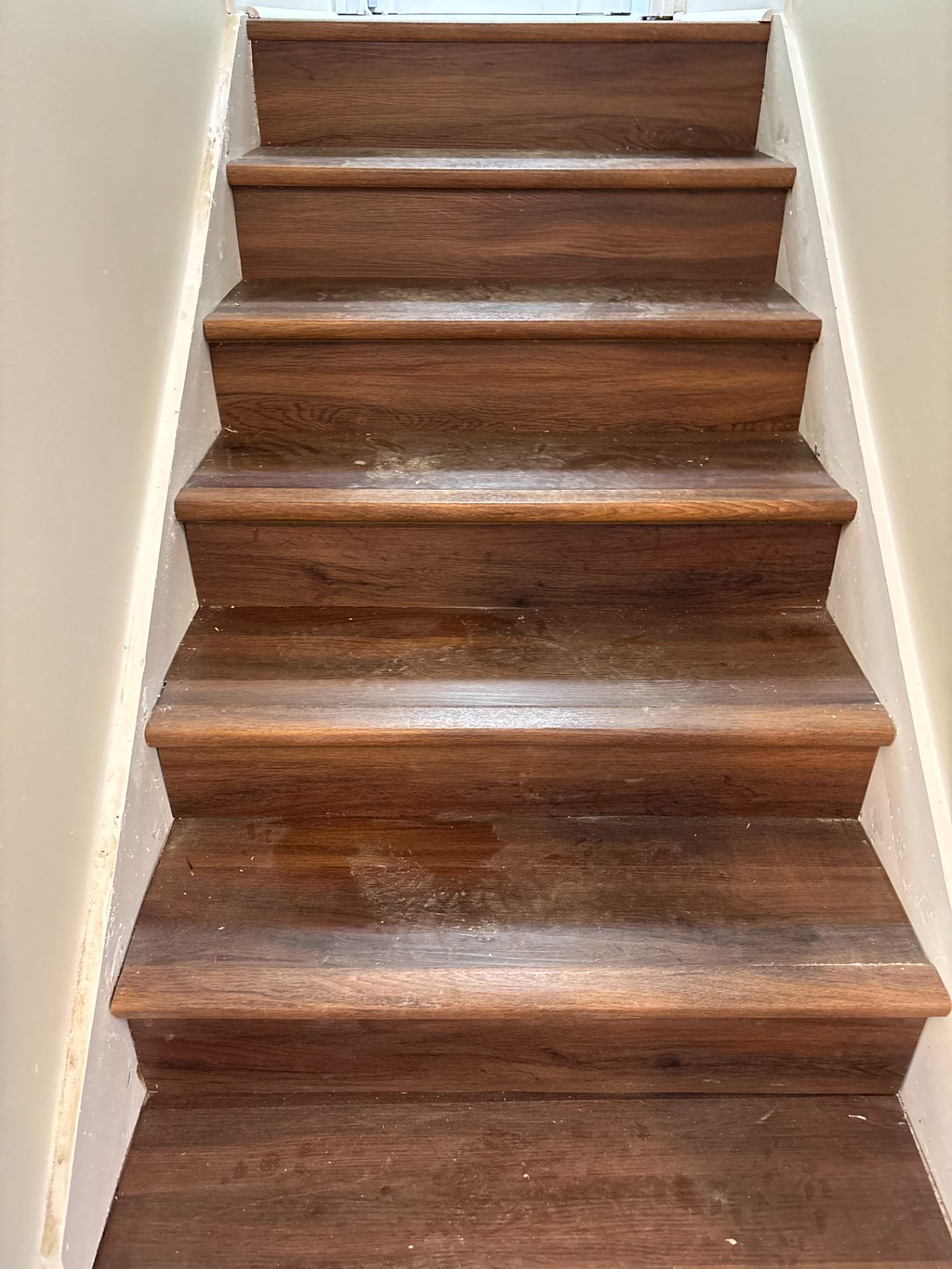 New wood stair treads installed against white risers