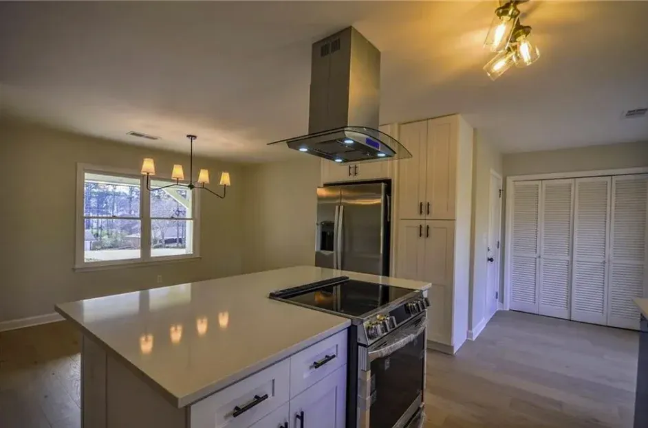 Island with a stainless hood above and a range set into the run behind