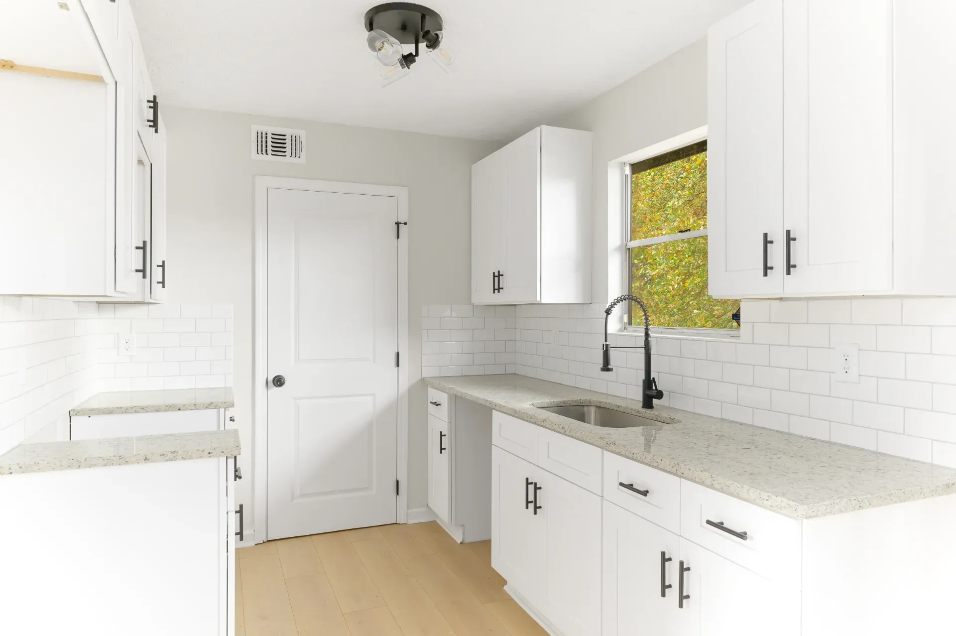 Compact kitchen with white cabinets and a tiled backsplash in Dunwoody