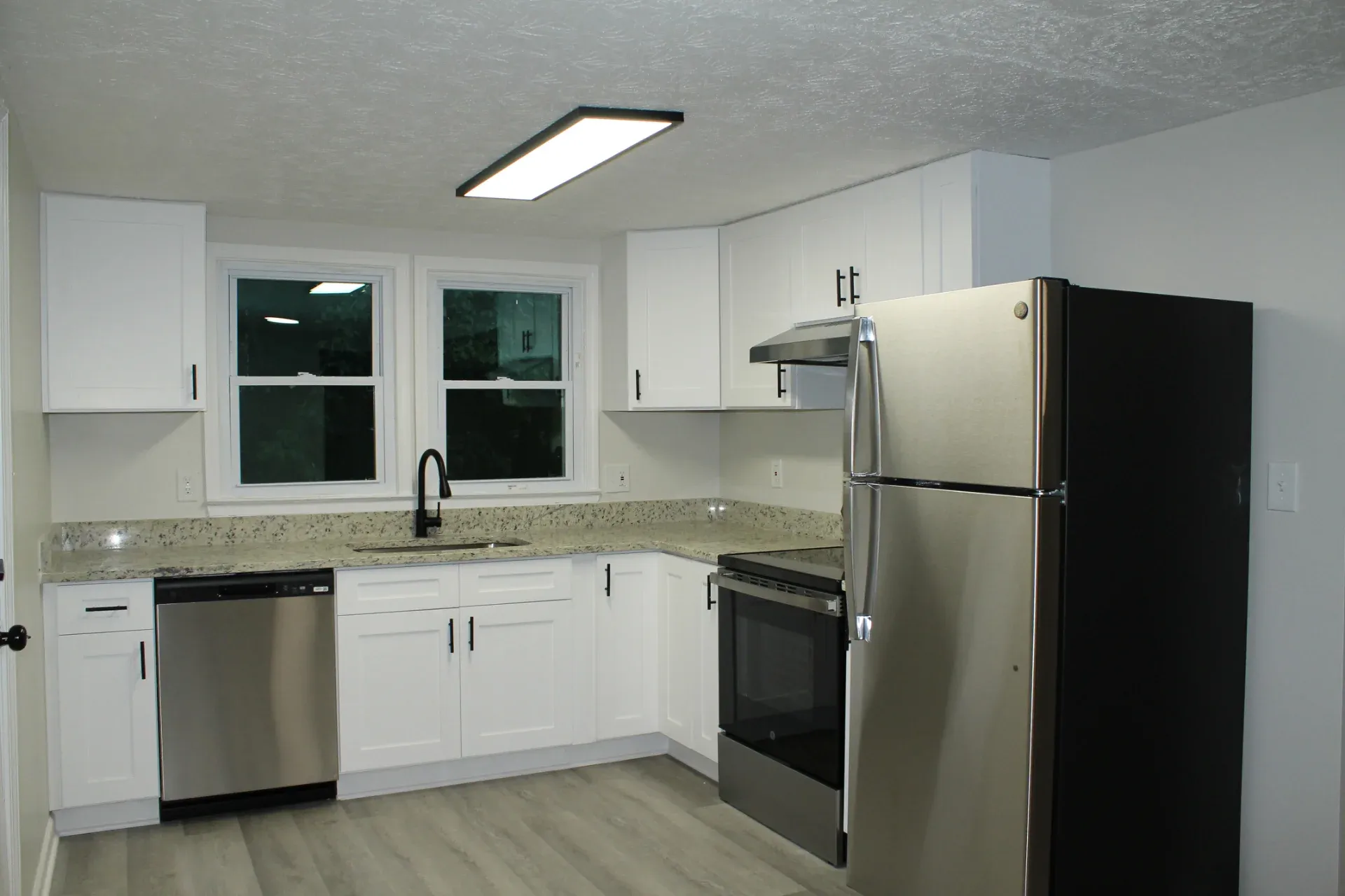 Kitchen with white cabinets, a stainless fridge and plank flooring in Smyrna
