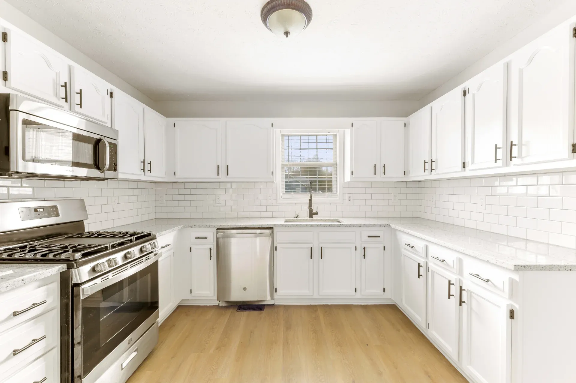 Galley kitchen with white cabinets and a window at the end in Dunwoody