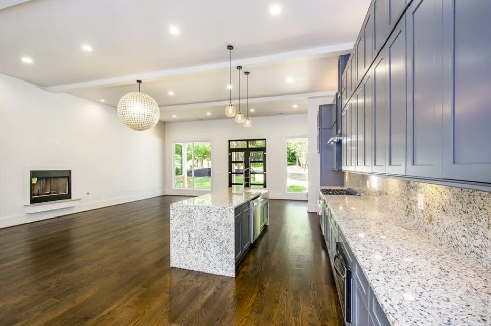 New kitchen with a stone island, gray cabinets and pendant lighting