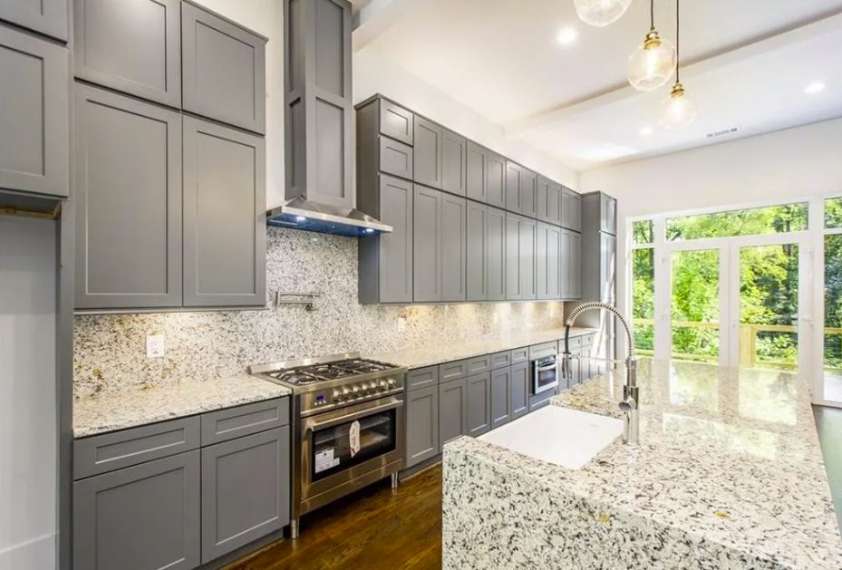 New kitchen with a stone island, gray cabinets and pendant lighting