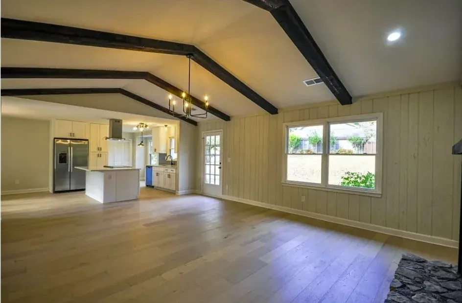 Vaulted room with exposed beams and new flooring throughout