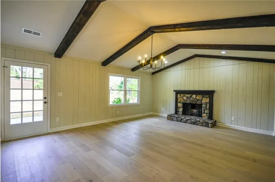 Vaulted living space with dark beams and a stone fireplace in Berkeley Lake