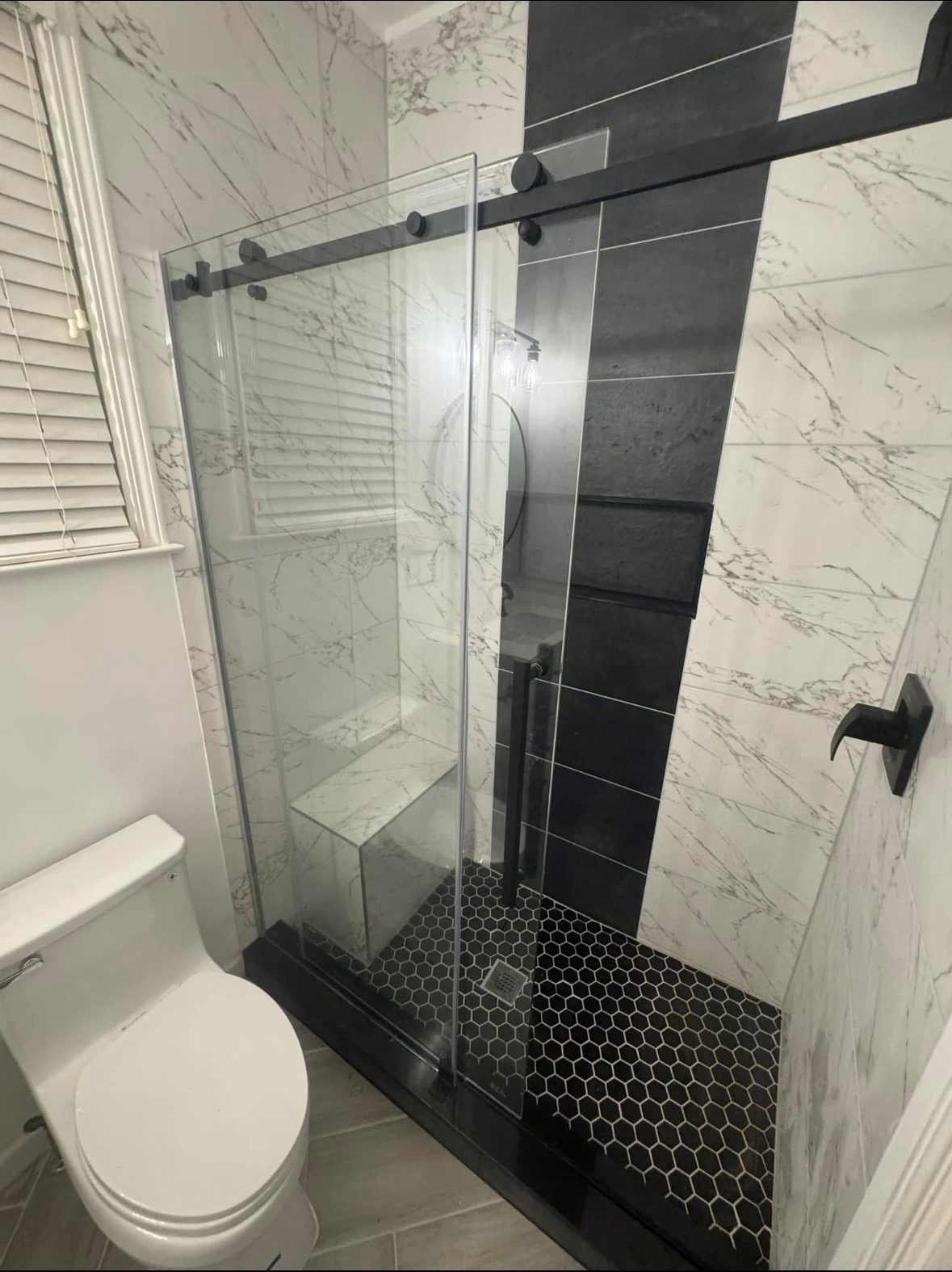 Tiled shower enclosure with frameless glass and a black fixture in Smyrna