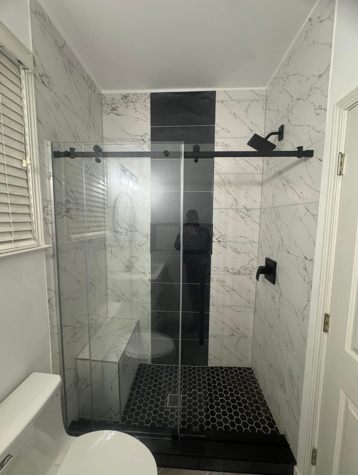 Tiled shower enclosure with frameless glass and a black fixture in Doraville