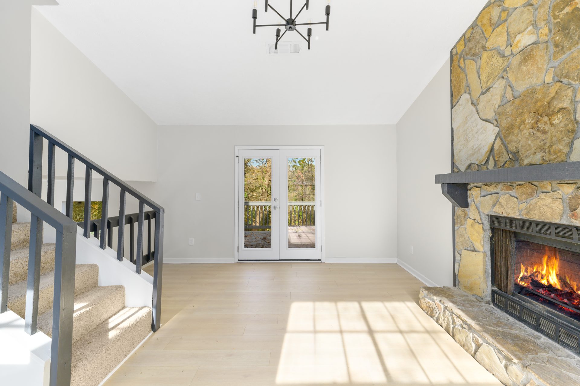 Renovated living space with a stone fireplace and an open staircase