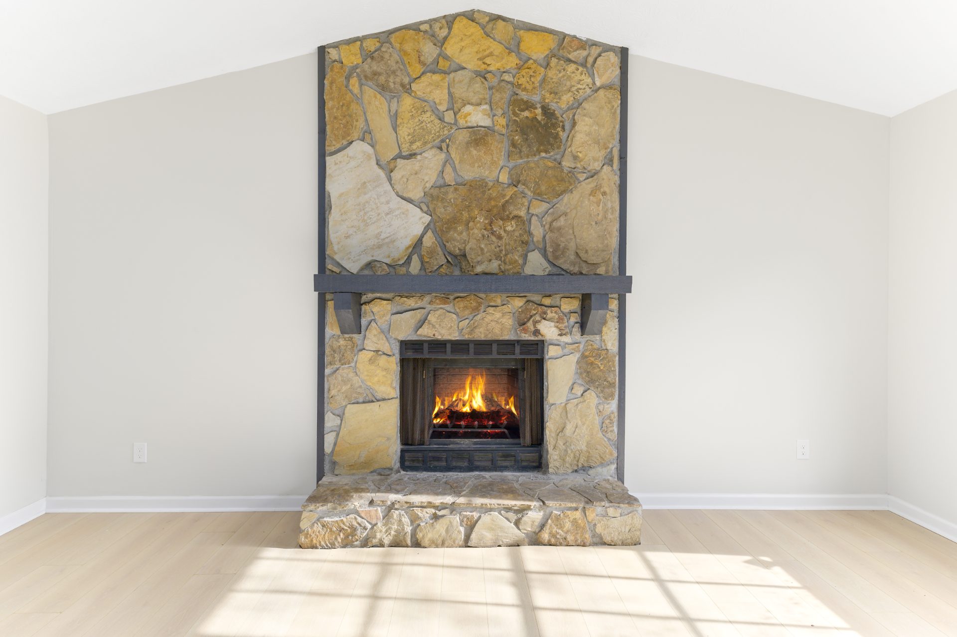 Renovated living space with a stone fireplace and an open staircase
