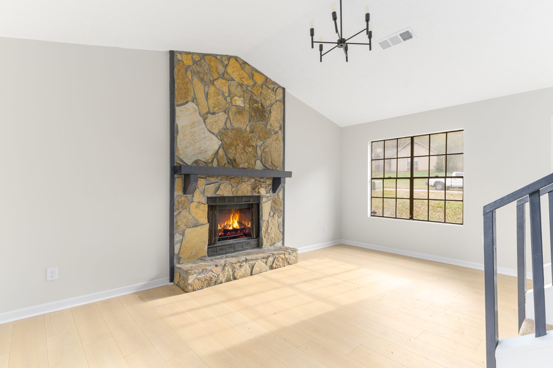 Renovated living space with a stone fireplace and an open staircase