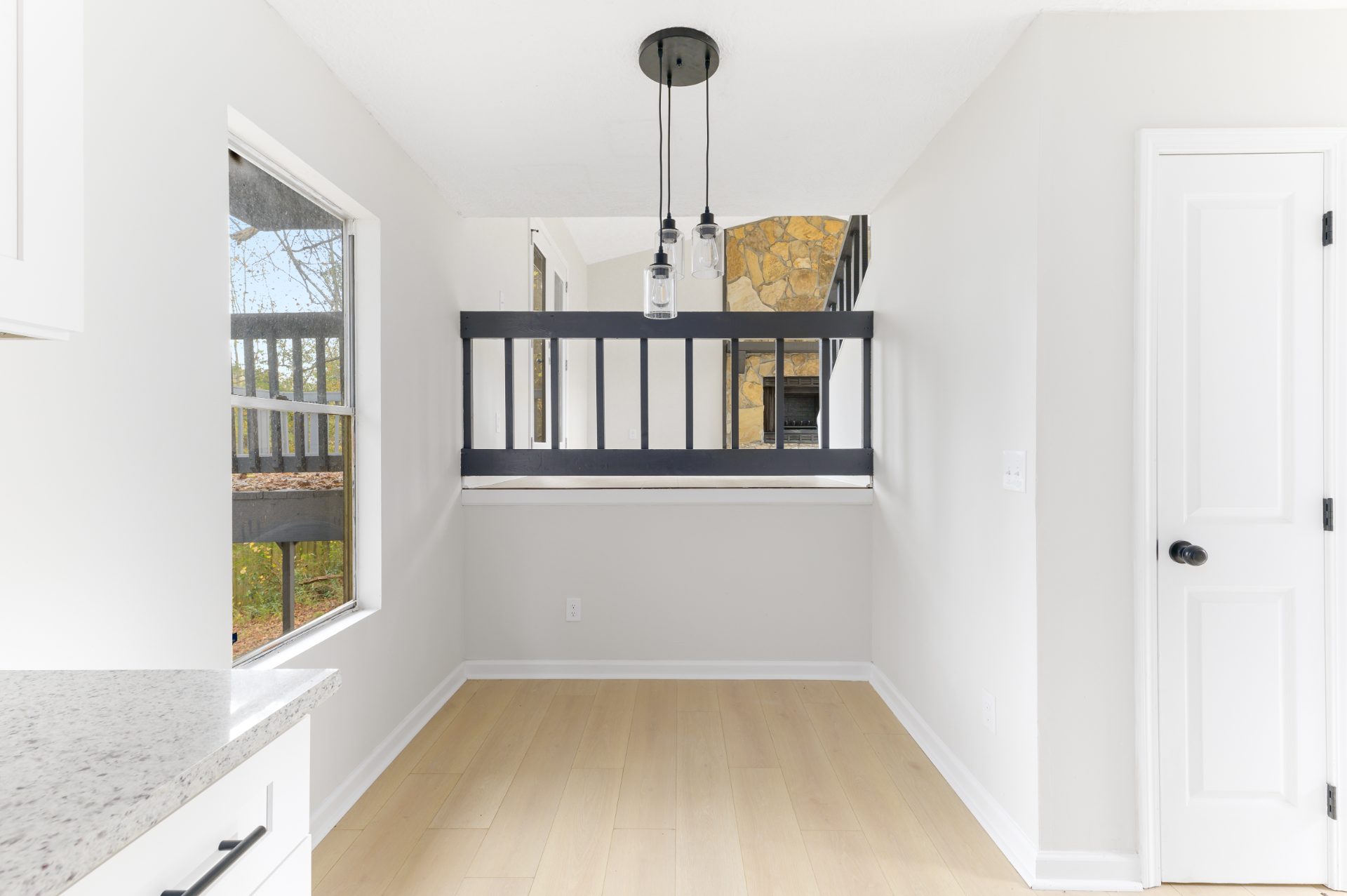 Renovated living space with a stone fireplace and an open staircase